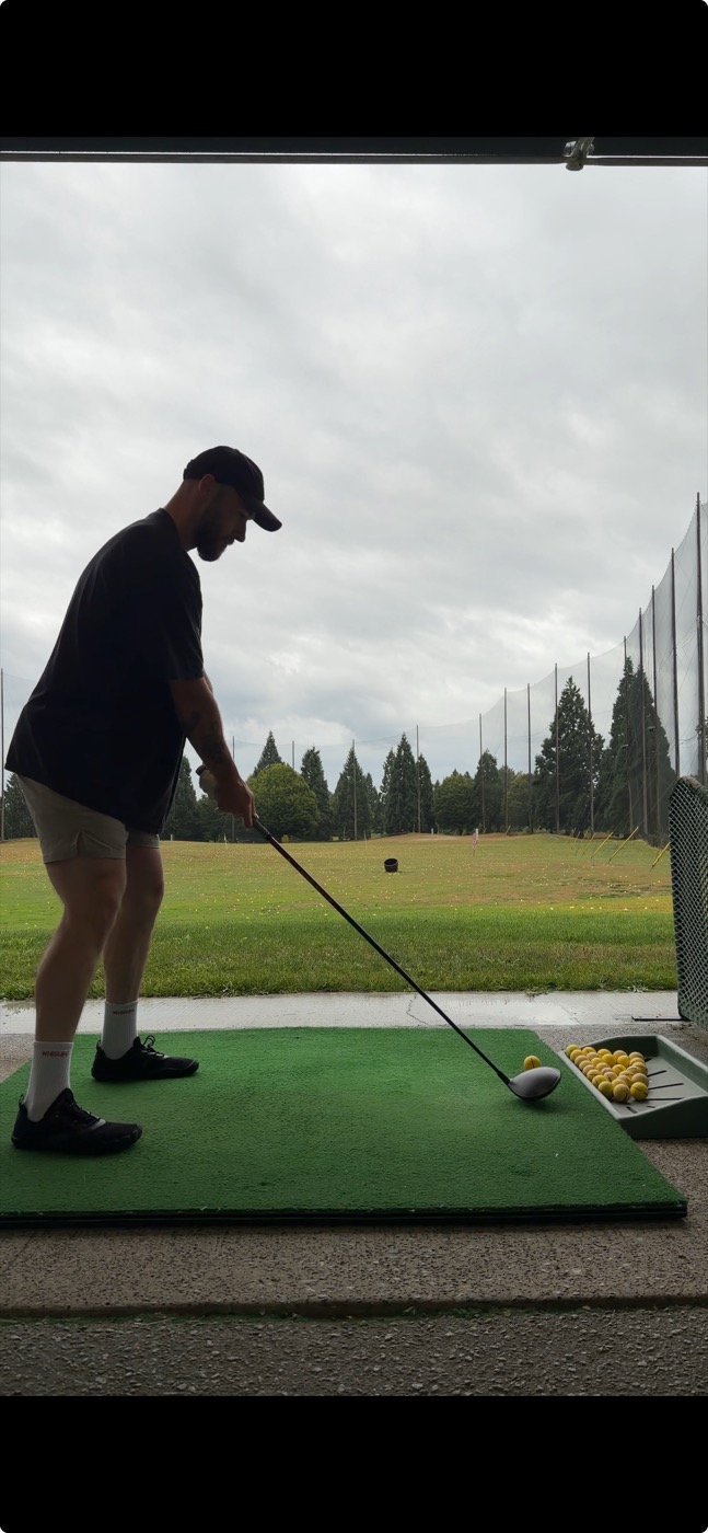 Ben hitting golf balls at the driving range